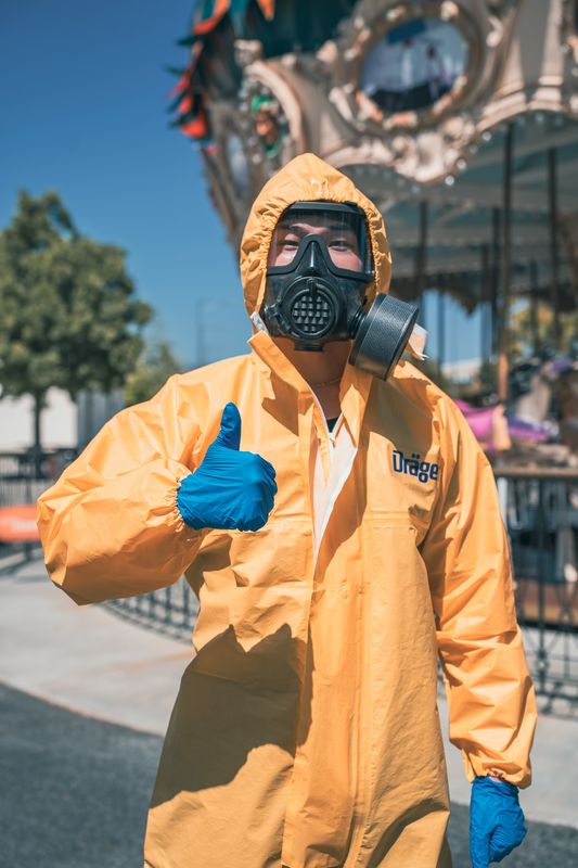 A figure in a yellow hazmat suit giving a thumbs up