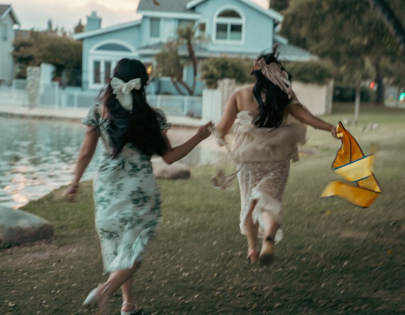 Two friends running across a lawn, laughing