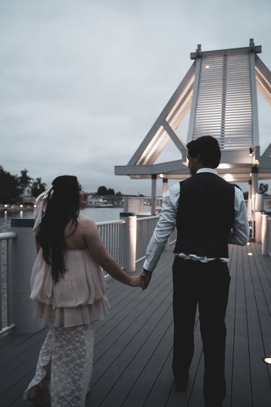 A couple walking away hand in hand toward a lit pavilion