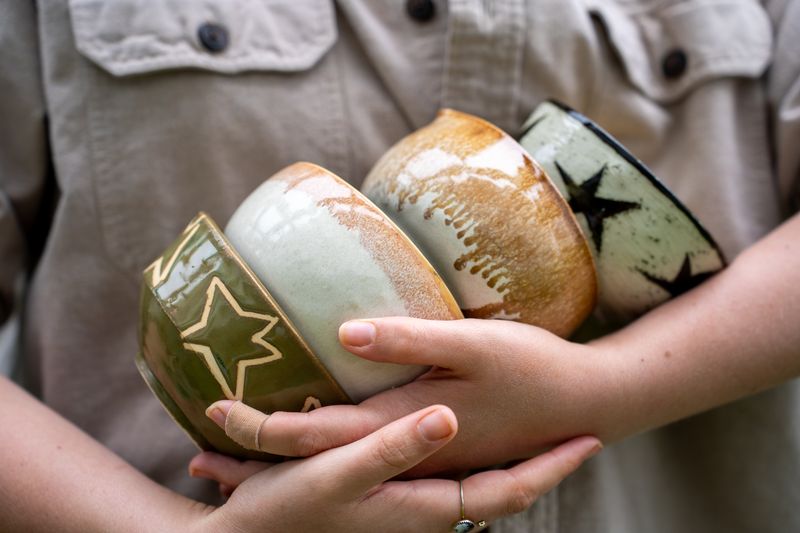 Hands holding a stack of handmade ceramic cups