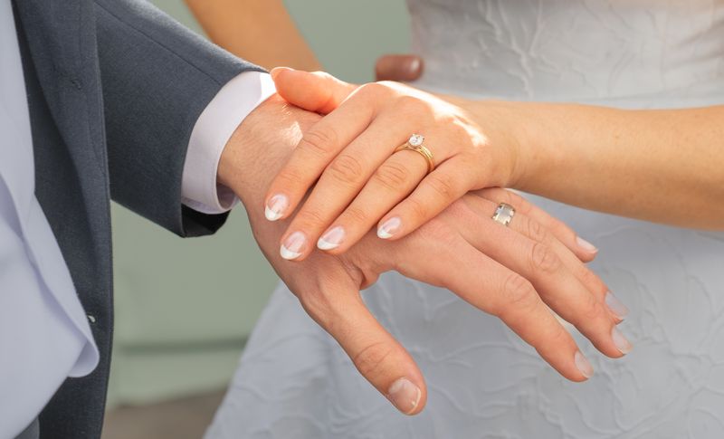 A groom holding his bride’s hand, showing her ring