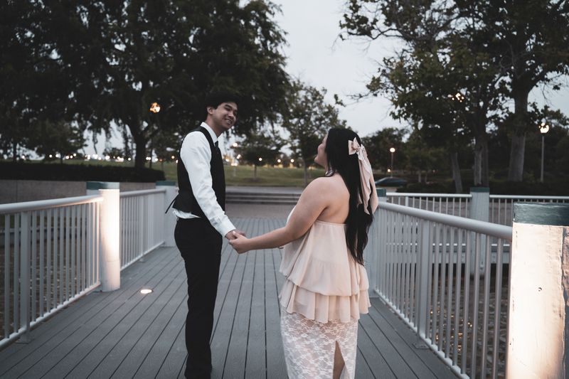 A couple holding hands on a dock at dusk