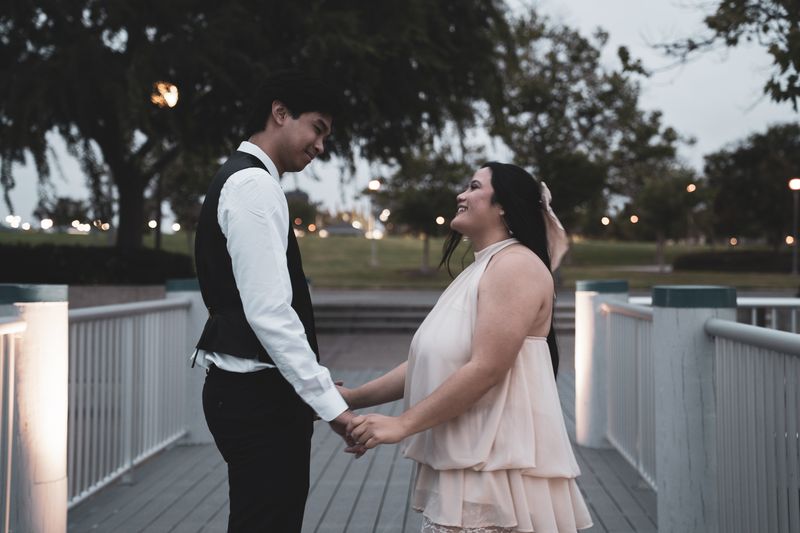 A couple facing each other on a dock at dusk